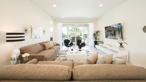 A modern living room with a sofa set, a coffee table, and a TV mounted on the wall. - Contemporary Disney Vacation Home - 5 min to Disney (Kissimmee)