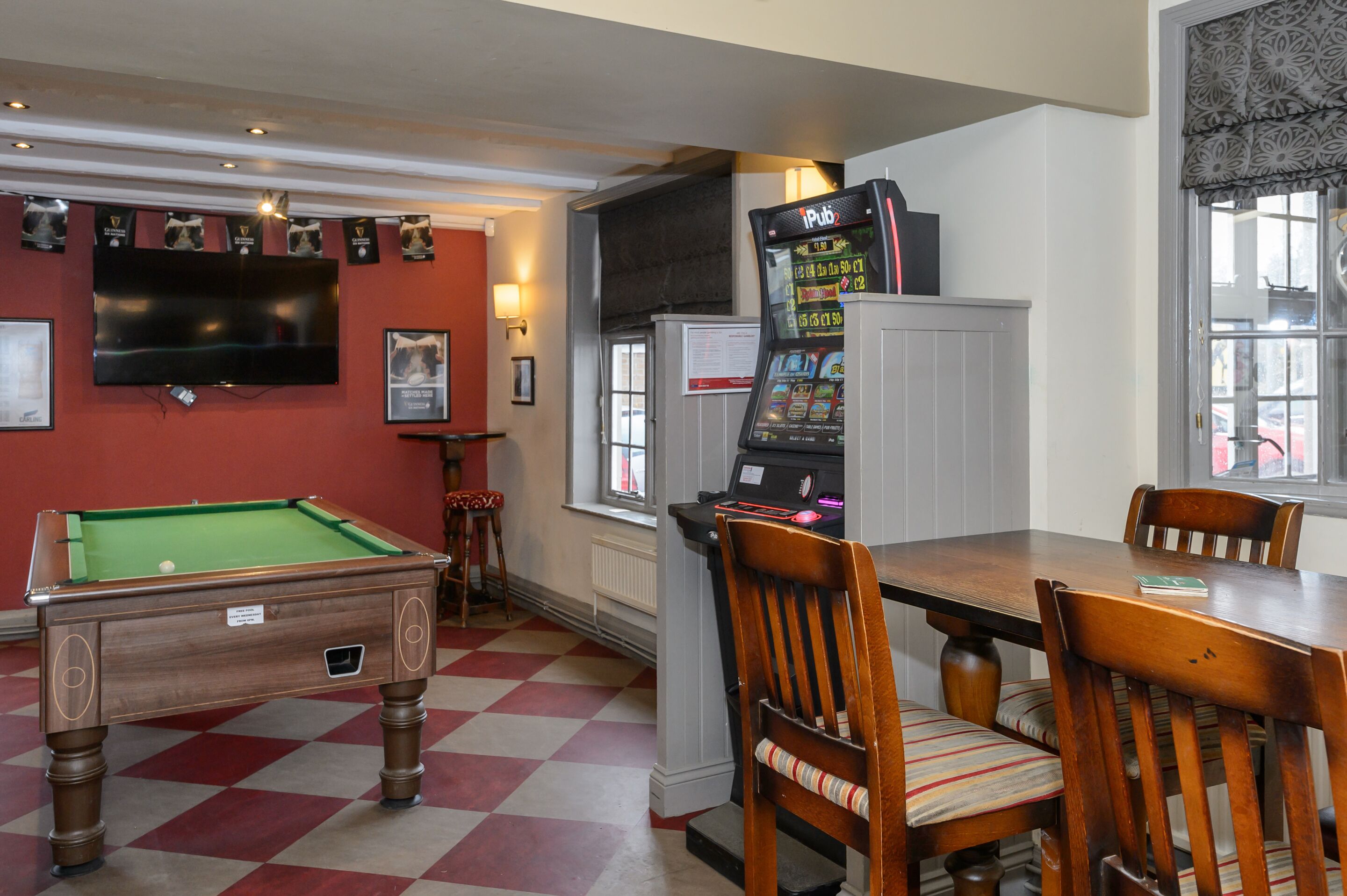 A billiards table, a pool table, and a gaming machine in a room with a checkered floor.