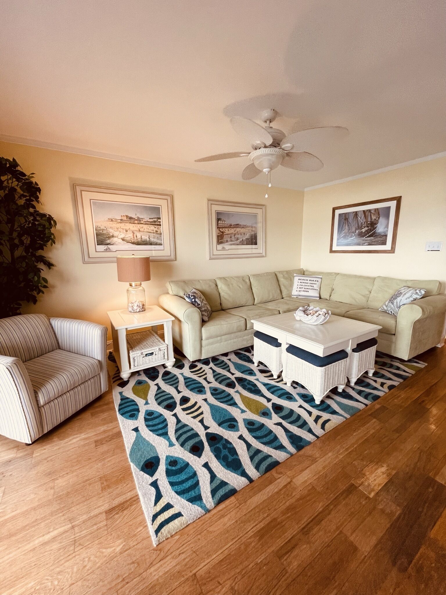 A living room with a beige sofa, striped armchair, white coffee table, and a patterned rug.