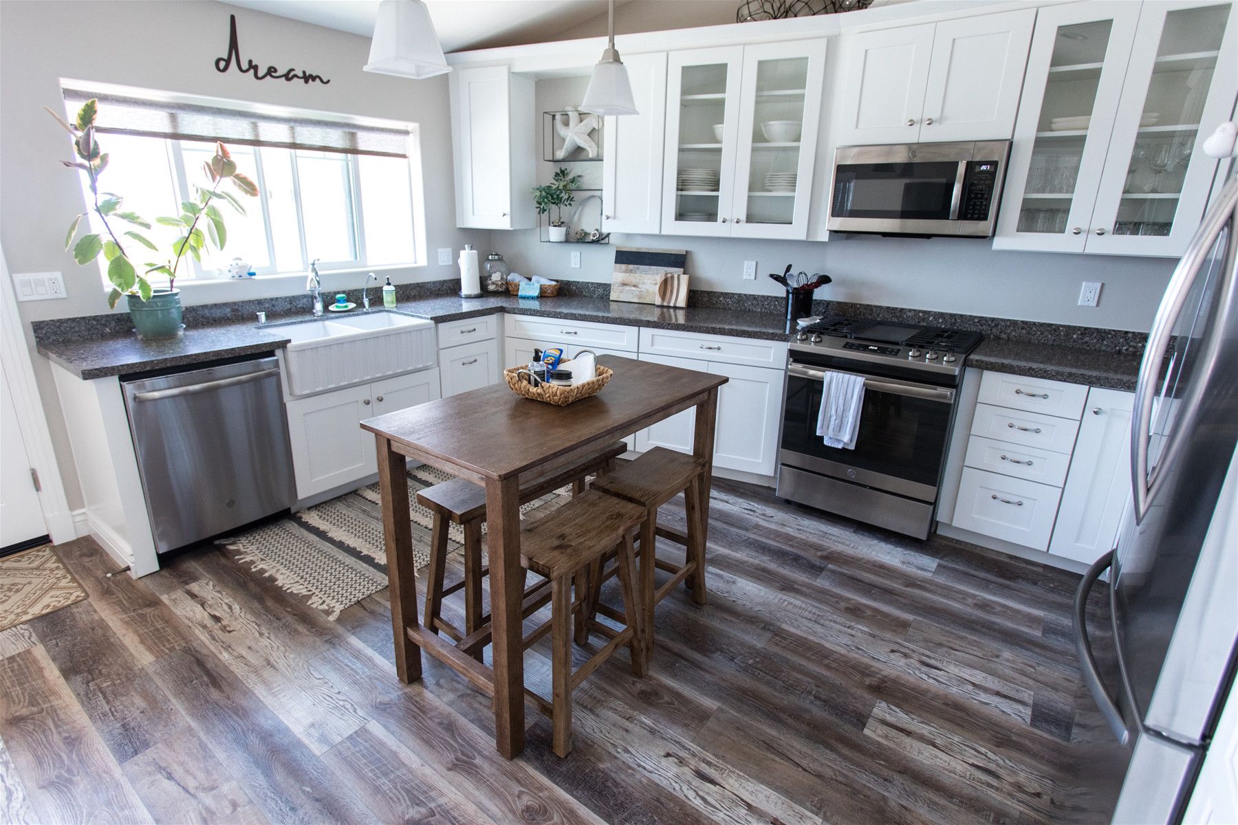 A kitchen with white cabinets, a wooden table, and a stainless steel refrigerator.