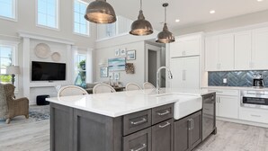 A spacious kitchen with a large island, white cabinetry, and stainless steel appliances. - Amie House BEACH Getaway *GOLF CART ONSITE* (Anna Maria)