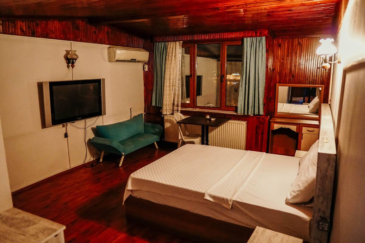 Ein Zimmer mit einem Bett, einem Fernseher, einem Schreibtisch und einem Sessel.
