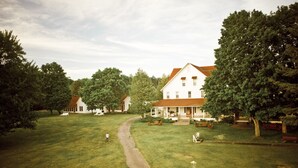 A large, white building with a red roof, surrounded by lush green trees and a well-maintained lawn. - Fountain Point - Cottage 14 (Lake Leelanau)