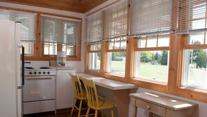 Une cuisine équipée d’une cuisinière, d’un réfrigérateur et de stores en bois aux fenêtres.
