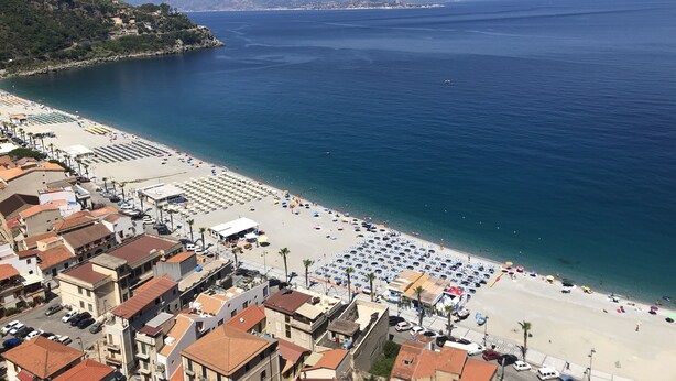 A coastal town with a beach, buildings, and a clear view of the sea.