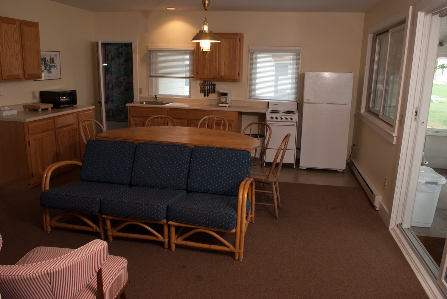 A compact kitchen with a dining area, including a sofa, chairs, and a refrigerator.