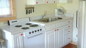 Une cuisine avec des meubles blancs, une cuisinière, un évier et un réfrigérateur.