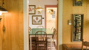 Un comedor acogedor con una mesa y sillas de madera, un tapete estampado y un cuadro en la pared.