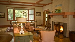 Una sala de estar acogedora con chimenea, vigas de madera, un sofá, sillas y una mesa.