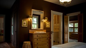 Un dormitorio con cómoda de madera, una cama con ropa blanca y un espejo sobre la cómoda.