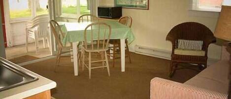 A dining area with a table and chairs, a television, and a painting on the wall.
