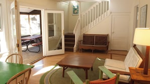 A cozy living room with a staircase, a sofa, a table, and a chair.