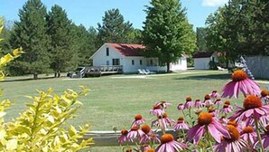 A house with a red roof, surrounded by trees and a grassy yard. - Fountain Point - The Dorm (Lake Leelanau)