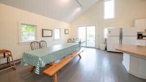 A spacious kitchen with a wooden bench and table, a refrigerator, and a view of the outdoors. - Fountain Point - The Dorm (Lake Leelanau)