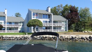 Un barco atracado cerca de un muelle con un edificio de varios pisos que tiene balcones y una bandera.