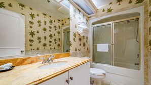 Ein Badezimmer mit Marmorwaschtisch, Toilette und einer Duschkabine.