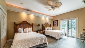 Ein Hotelzimmer mit zwei Betten, einem Deckenventilator und einem großen Fenster mit Jalousien.