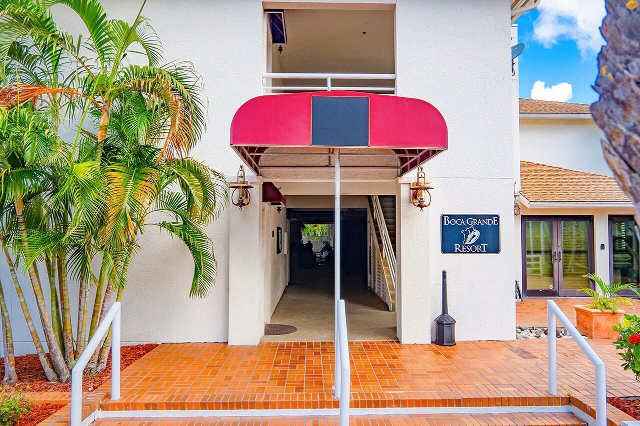 L'ingresso di un edificio con un tenda rossa, una insegna per Boca Grande Resort e una scala che conduce a un piano superiore.