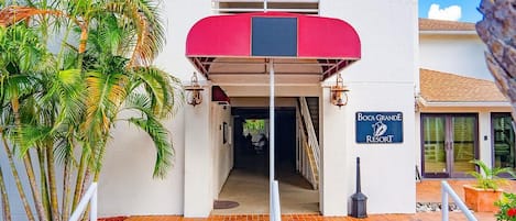 L'ingresso di un edificio con un tenda rossa, una insegna per Boca Grande Resort e una scala che conduce a un piano superiore.