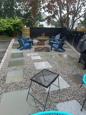 A patio area with blue Adirondack chairs, a fire pit, and a grill. - Contemporary  Elegance Meets Coastal decor (Kennebunk)