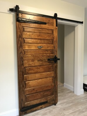 A wooden sliding barn door with a metal handle and a metal track. - Contemporary  Elegance Meets Coastal decor (Kennebunk)