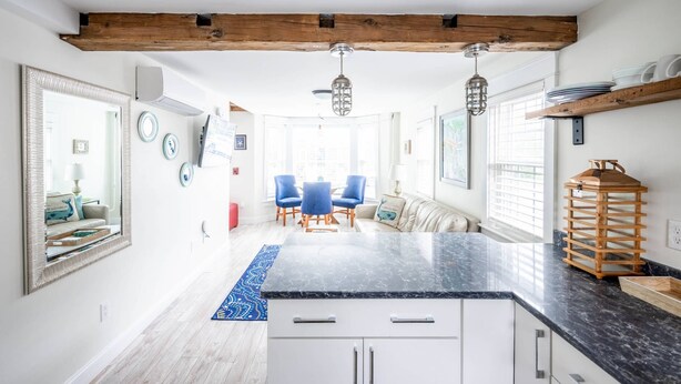 A modern kitchen with white cabinets, a black countertop, and wooden beams on the ceiling. - Contemporary  Elegance Meets Coastal decor (Kennebunk)