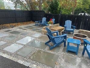 A patio area with stone flooring, blue Adirondack chairs, a fire pit, and a small table with a potted plant. - Contemporary  Elegance Meets Coastal decor (Kennebunk)