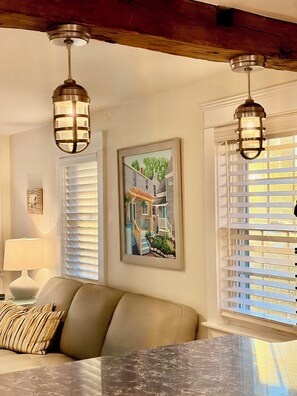 A room with a sofa, a framed picture, and two hanging light fixtures. - Contemporary  Elegance Meets Coastal decor (Kennebunk)