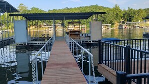 Un muelle de madera que lleva a una zona cubierta con vistas al lago y a las embarcaciones.