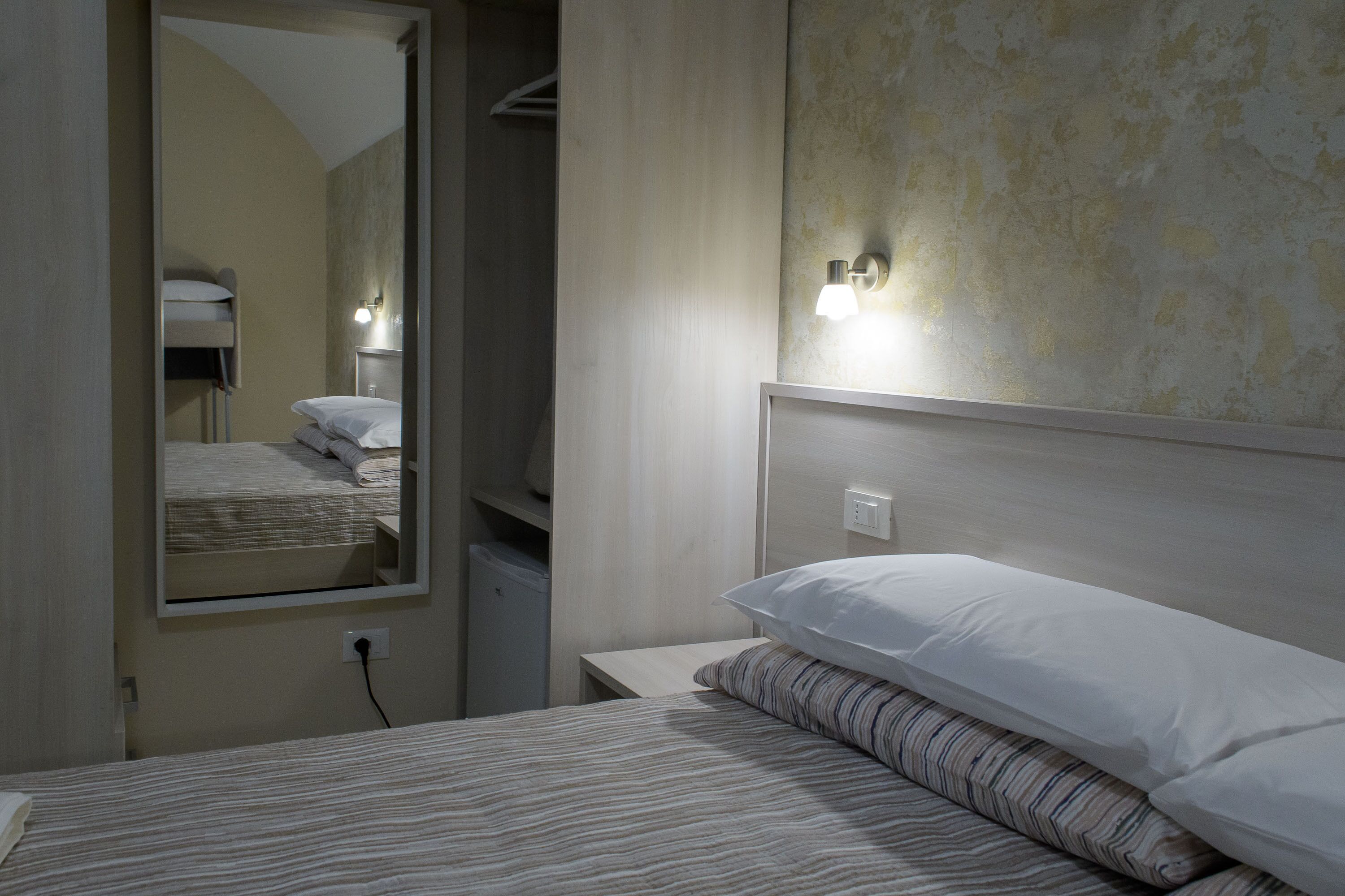 Une chambre à coucher avec un lit, une table de chevet, un miroir et une armoire.
