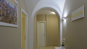 Un pasillo con una puerta, un cuadro con un paisaje urbano enmarcado y un letrero que dice "NATUR VATOR".