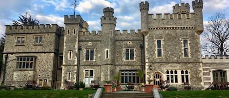 A castle-like building with multiple towers, a central entrance with steps, and stone walls.