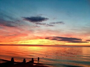 Ein Sonnenuntergang über einem ruhigen Meer mit einer sich ins Wasser erstreckenden Mole.