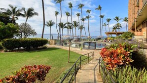 A hotel courtyard with palm trees, a pool, and a view of the ocean.