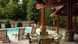 A poolside area with lounge chairs and a table, surrounded by a wooden pergola and stone pillars. - Dollywood pigeon forge Cabin, Pools, Game Room, Hot tub, 0.5 mile to Parkway (Pigeon Forge)