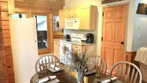 A compact kitchen with wooden cabinets, a microwave, and a stove. There is a dining table with chairs and a vase with dried plants. - Dollywood pigeon forge Cabin, Pools, Game Room, Hot tub, 0.5 mile to Parkway (Pigeon Forge)