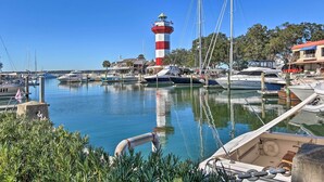 A marina with boats docked, a lighthouse, and buildings in the background. - Ocean-View Treetop Escape w/ Fire Pit! (Hilton Head)