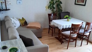 A cozy living room with a sofa, a dining table with chairs, a wooden coffee table, and a potted plant. - Vacation apartment, good location in the mining region Erzgebirge, mountain town Schneeberg (Schneeberg, Sachsen, Deutschland)