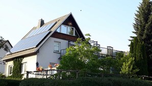 A house with solar panels, a balcony, and a garden. - Vacation apartment, good location in the mining region Erzgebirge, mountain town Schneeberg (Schneeberg, Sachsen, Deutschland)
