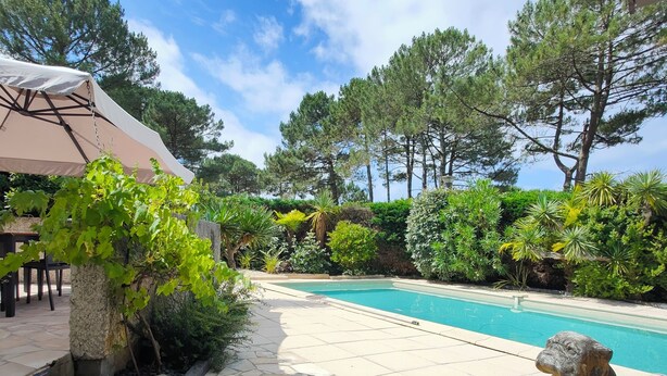 A pool area with stone tiles, a pergola with a white canopy, and a stone statue. - Air-conditioned "Carmen" villa with heated pool near the ocean (Biscarrosse)