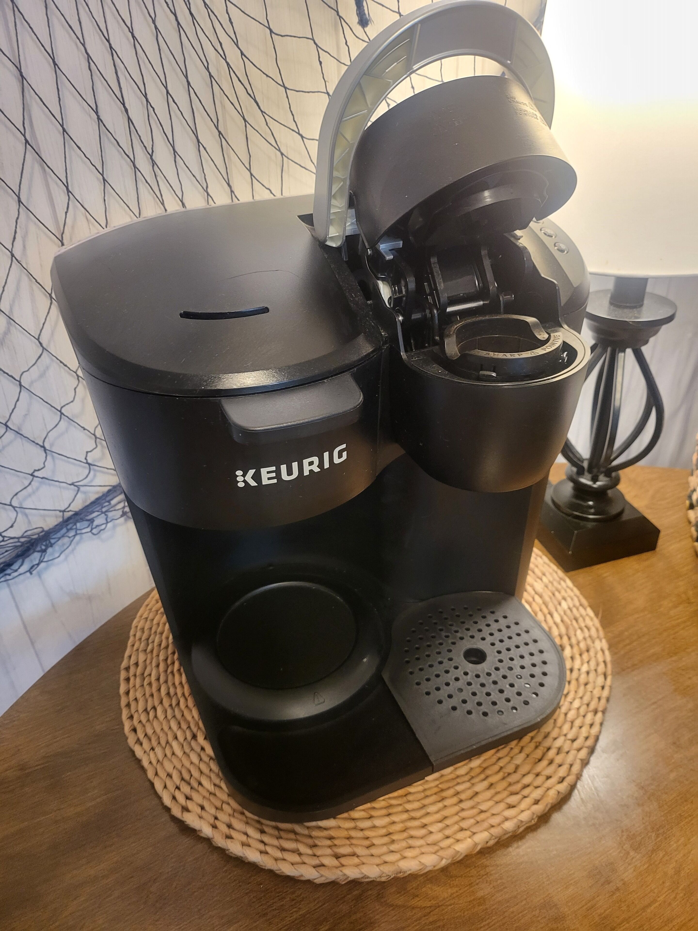 A Keurig coffee maker on a woven placemat.