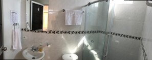 A bathroom with a glass shower enclosure, a sink, and a toilet.