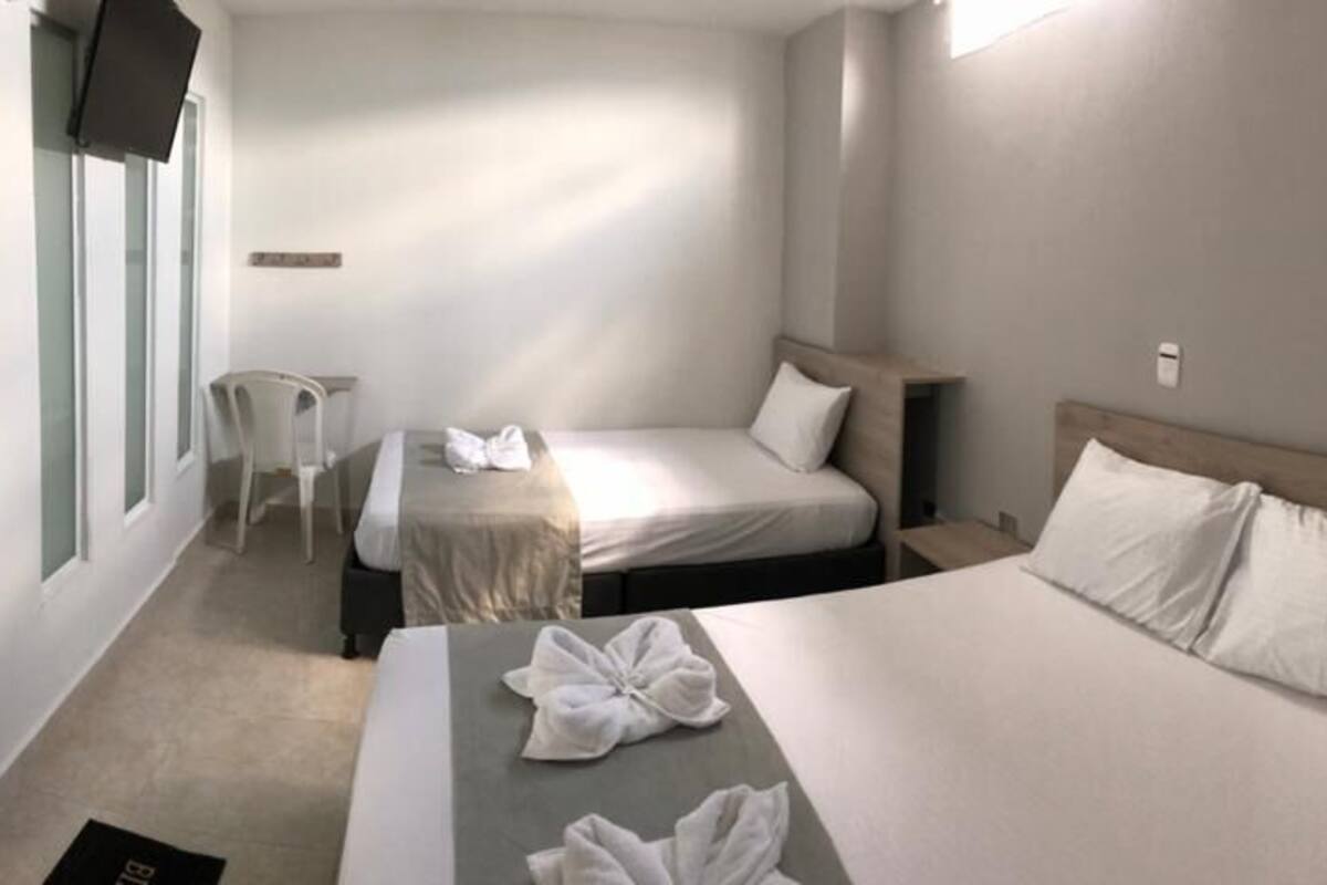A hotel room with two beds, a desk, and a chair.
