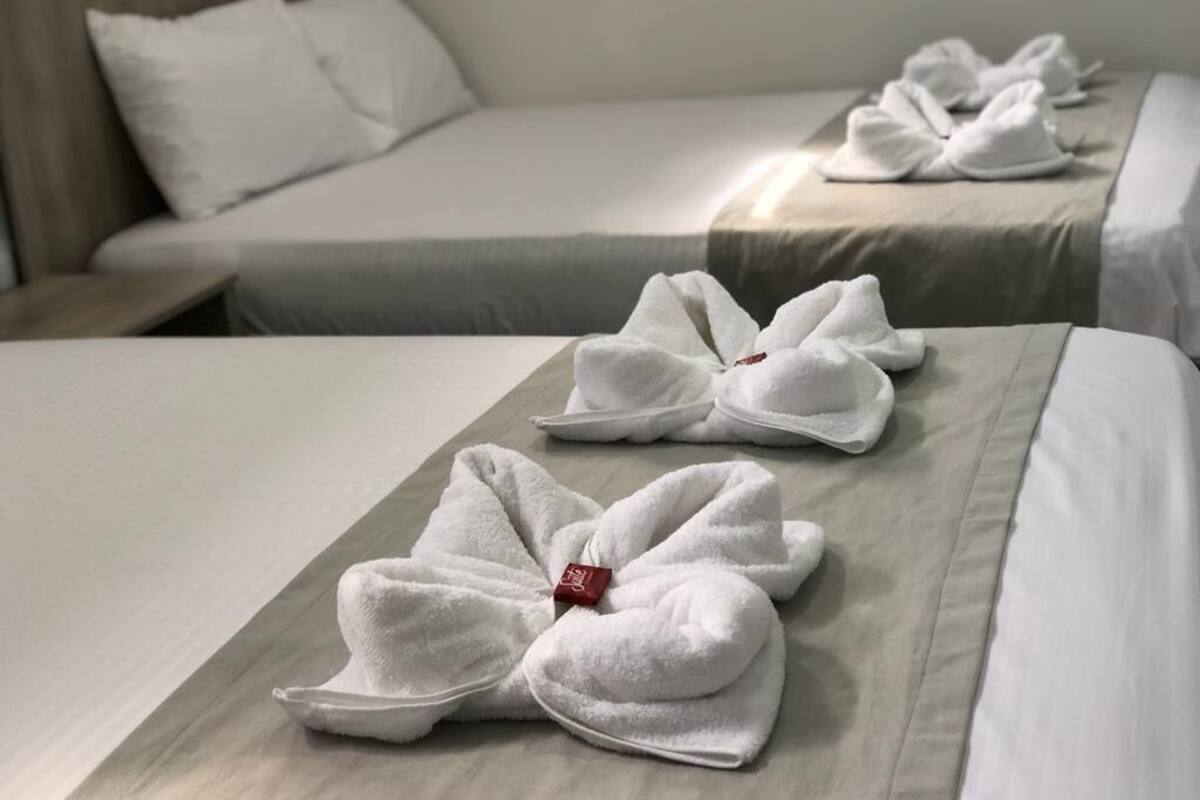 A hotel room with neatly arranged towels on the beds.