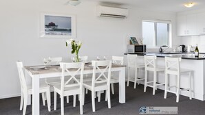 A modern kitchen with white cabinetry, a dining area with white chairs, and a ceiling fan. - Seacombe Grove, Ventnor with open fire, balcony stunning ocean views (Ventnor)