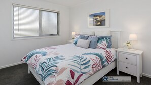 A bedroom with a bed, two bedside tables, a nightstand, a window with blinds, a wall-mounted picture, and a ceiling light. - Seacombe Grove, Ventnor with open fire, balcony stunning ocean views (Ventnor)