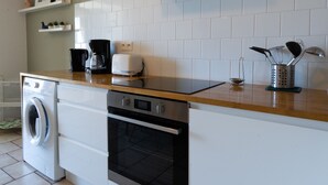 Eine Küche mit Waschmaschine, Backofen und Kaffeemaschine.