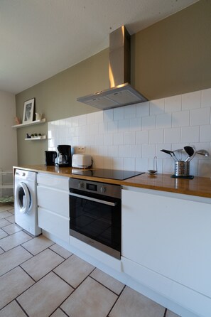A kitchen with a washing machine, oven, and coffee maker.
