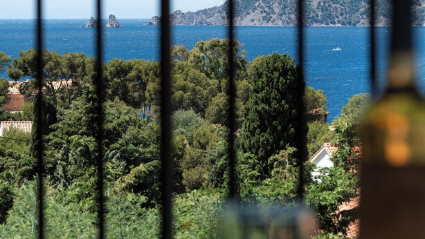 Ein Balkon mit Blick auf eine Küstenlandschaft, einschließlich eines Hügels und dem Meer.