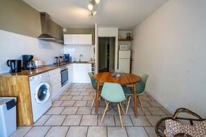 A compact kitchen with a washing machine, a coffee maker, and a microwave.